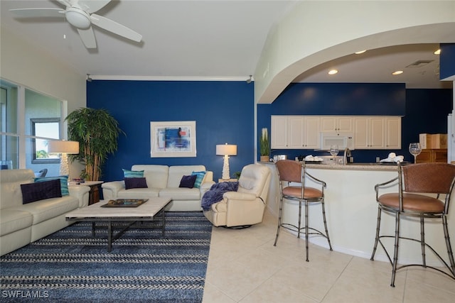 living room featuring ceiling fan, light tile patterned floors, and crown molding