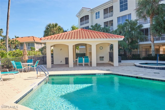 rear view of house with a swimming pool with hot tub and a patio