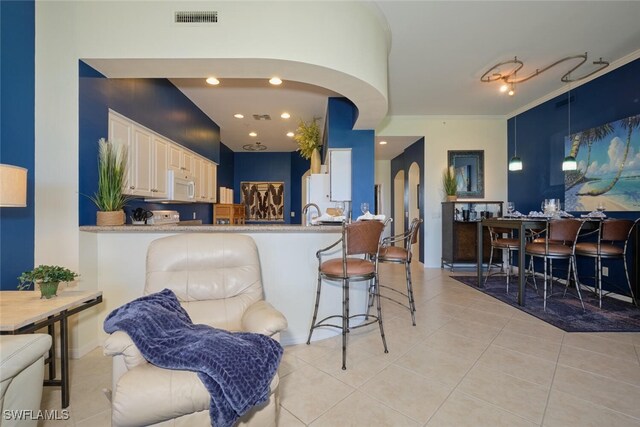 kitchen featuring a breakfast bar, kitchen peninsula, crown molding, and light tile patterned floors