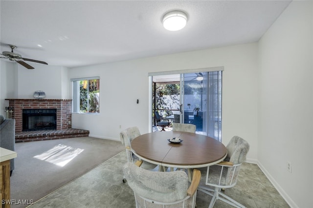 dining room featuring ceiling fan, light colored carpet, a wealth of natural light, and a brick fireplace