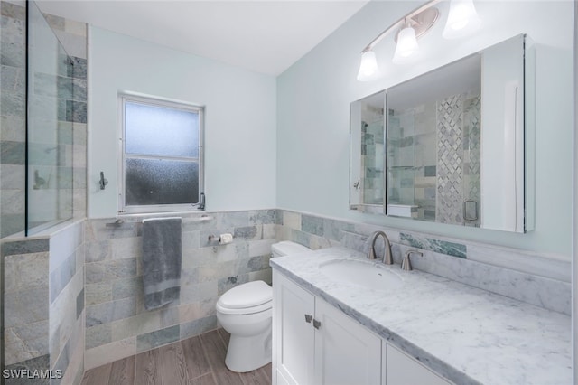 bathroom featuring an enclosed shower, vanity, wood-type flooring, tile walls, and toilet