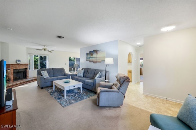 carpeted living room with a fireplace, a textured ceiling, and ceiling fan