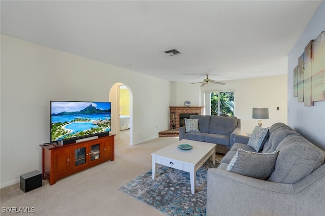 living room featuring ceiling fan, a fireplace, and light colored carpet