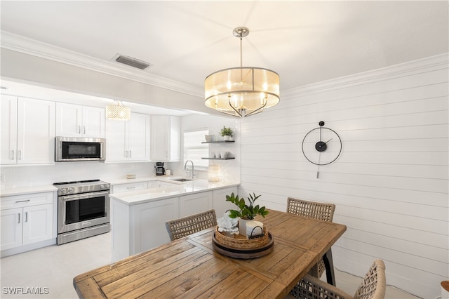 kitchen with sink, hanging light fixtures, stainless steel appliances, kitchen peninsula, and white cabinets