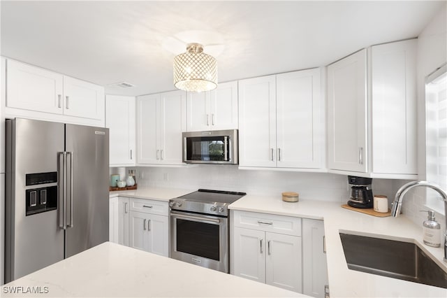 kitchen with tasteful backsplash, sink, white cabinets, and stainless steel appliances