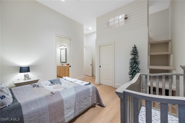 bedroom with ensuite bathroom and hardwood / wood-style floors