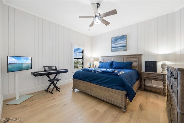 bedroom with light hardwood / wood-style flooring, ceiling fan, crown molding, and wood walls