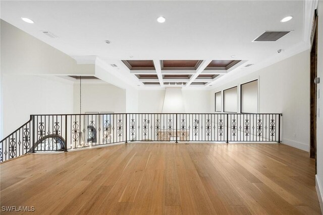 spare room with beam ceiling, light hardwood / wood-style floors, coffered ceiling, and ornamental molding