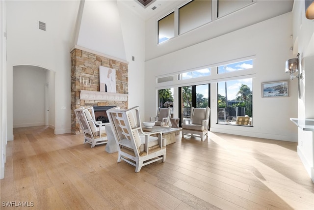 living room featuring light hardwood / wood-style floors, a towering ceiling, and a fireplace