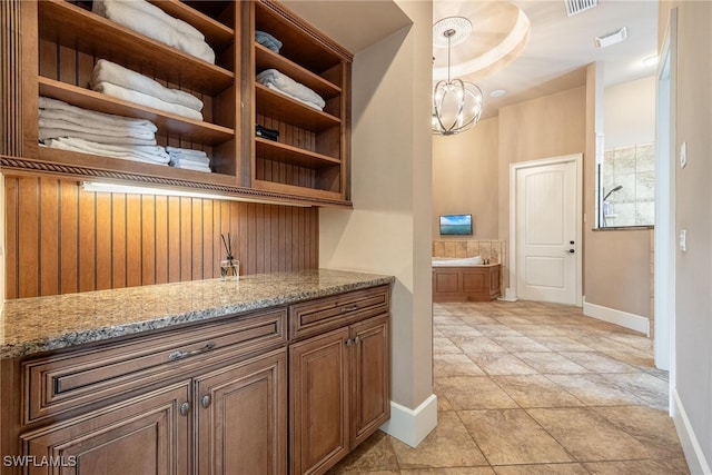 bar featuring decorative light fixtures, light stone countertops, light tile patterned floors, and an inviting chandelier