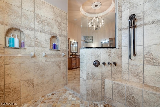 bathroom featuring a chandelier, vanity, and tiled shower