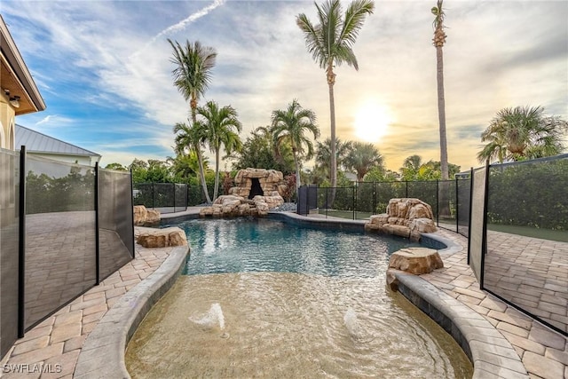 pool at dusk with pool water feature and a patio