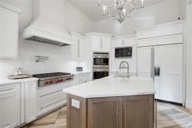 kitchen with white cabinets, built in appliances, premium range hood, and a kitchen island