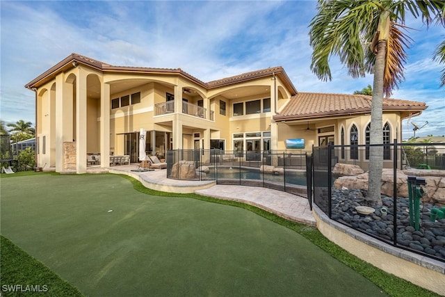 rear view of house with a fenced in pool, a balcony, and a patio