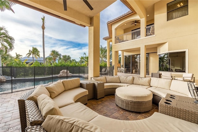 view of patio with outdoor lounge area, a fenced in pool, pool water feature, ceiling fan, and a balcony