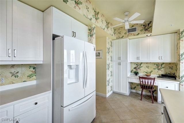 kitchen featuring ceiling fan, white fridge with ice dispenser, light tile patterned floors, white cabinets, and built in desk