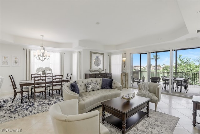 living room featuring light tile patterned floors, a tray ceiling, and a notable chandelier