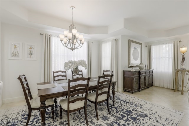 tiled dining space featuring a tray ceiling and an inviting chandelier