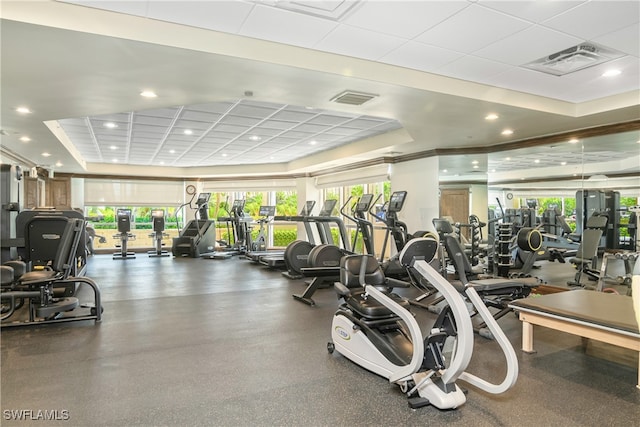 gym featuring a tray ceiling and ornamental molding