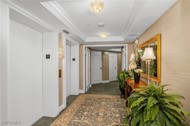 hallway with elevator, a raised ceiling, and crown molding