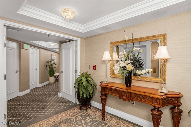 corridor featuring a raised ceiling, crown molding, and carpet floors