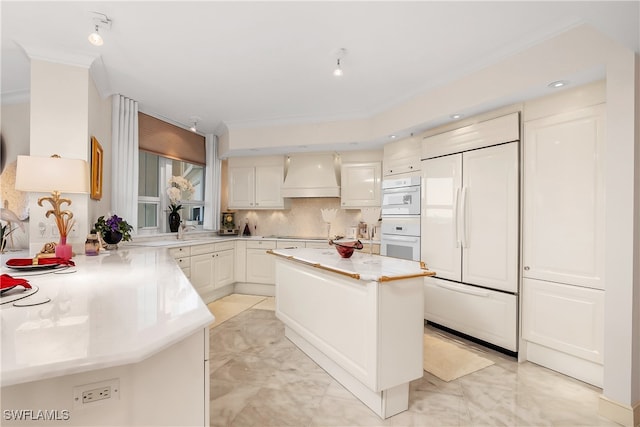 kitchen featuring backsplash, ornamental molding, custom range hood, white appliances, and a kitchen island