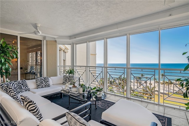 sunroom featuring ceiling fan and a water view