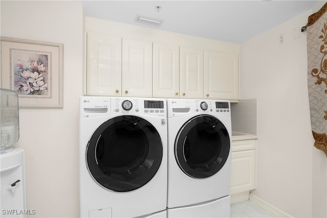 washroom featuring cabinets and washing machine and clothes dryer