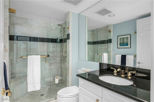 bathroom featuring a shower with door, vanity, and toilet