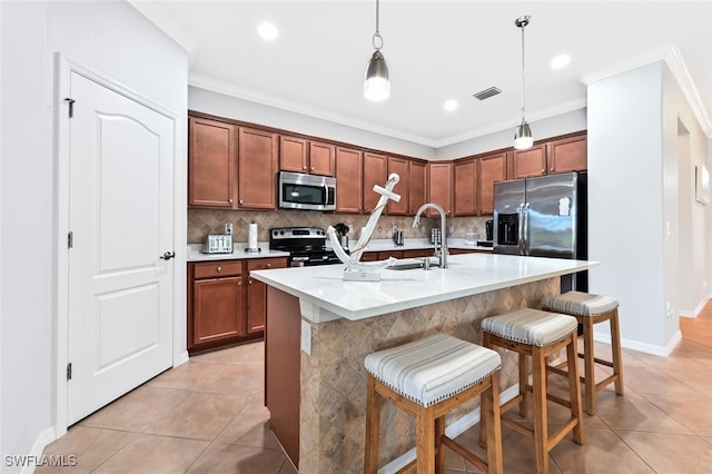 kitchen with a breakfast bar, a kitchen island with sink, sink, hanging light fixtures, and appliances with stainless steel finishes