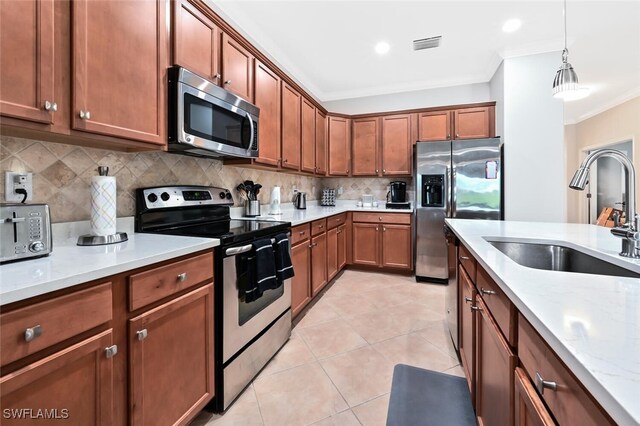 kitchen featuring light stone countertops, sink, hanging light fixtures, tasteful backsplash, and appliances with stainless steel finishes