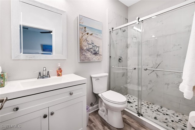 bathroom with hardwood / wood-style floors, vanity, toilet, and a shower with door