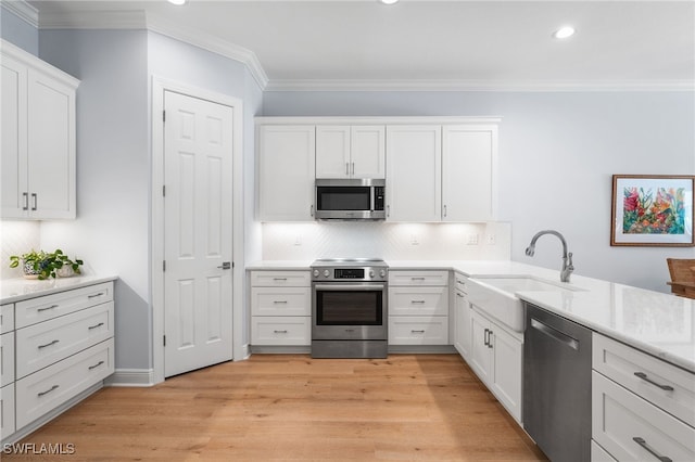 kitchen featuring white cabinetry, sink, stainless steel appliances, and ornamental molding