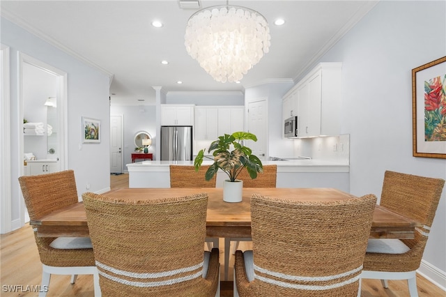 dining area with light wood-type flooring, crown molding, and an inviting chandelier