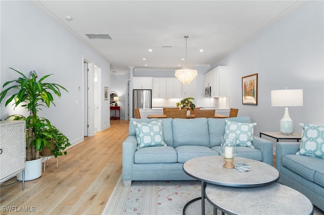 living room with an inviting chandelier, crown molding, and light hardwood / wood-style flooring