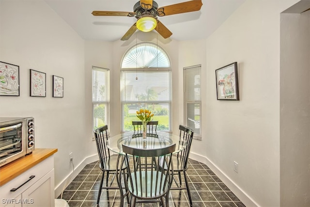 dining room featuring ceiling fan and dark tile patterned flooring