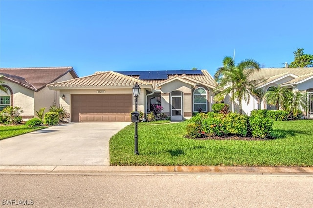 mediterranean / spanish-style home featuring solar panels, a front yard, and a garage