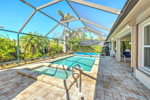 view of pool with a patio area, an in ground hot tub, and glass enclosure