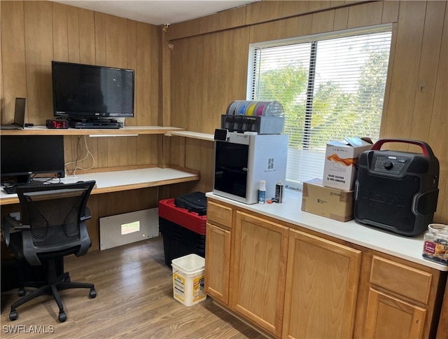 office space with wood walls, light hardwood / wood-style flooring, and built in desk