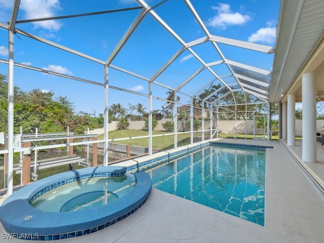 view of pool featuring glass enclosure, an in ground hot tub, and a patio