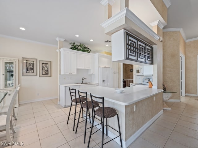 kitchen with a kitchen breakfast bar, ornamental molding, white appliances, sink, and white cabinets