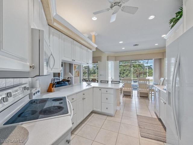 kitchen featuring light tile patterned floors, light countertops, white cabinets, white appliances, and a peninsula