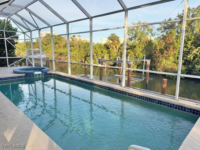 view of pool featuring glass enclosure and an in ground hot tub