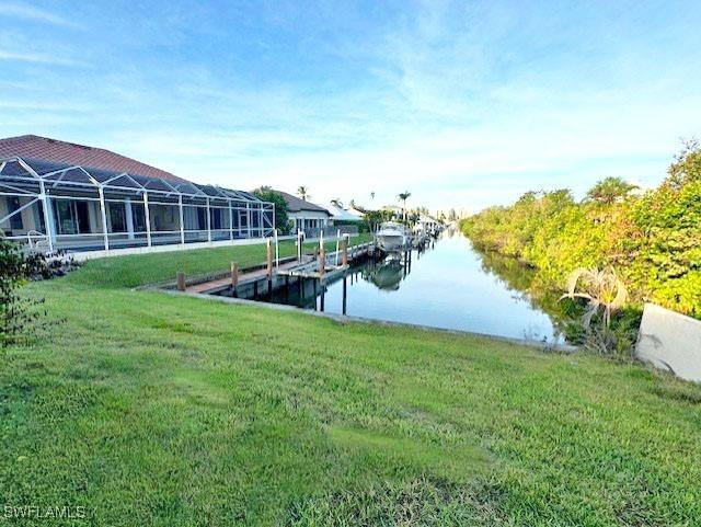 view of dock with a lawn and a water view