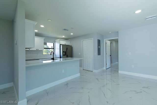 kitchen featuring sink, stainless steel refrigerator with ice dispenser, tasteful backsplash, white cabinetry, and kitchen peninsula