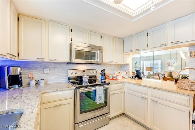 kitchen featuring decorative backsplash, light tile patterned floors, appliances with stainless steel finishes, light stone counters, and white cabinetry