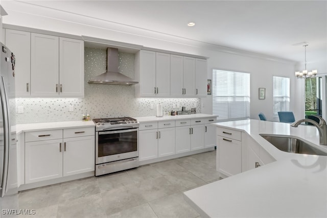 kitchen with pendant lighting, sink, wall chimney exhaust hood, decorative backsplash, and stainless steel appliances