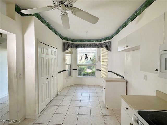 kitchen featuring light tile patterned flooring, ceiling fan, range with electric cooktop, and white cabinets