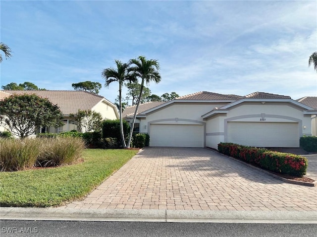 view of front of property with a garage, decorative driveway, a tiled roof, and stucco siding