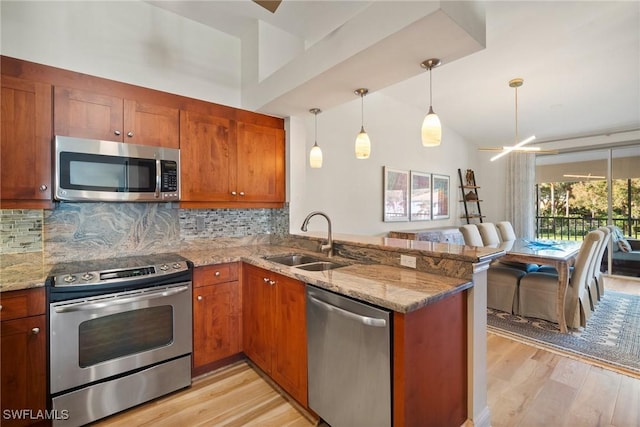 kitchen featuring stainless steel appliances, light stone countertops, sink, and kitchen peninsula